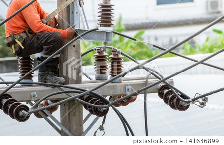 High voltage power line maintenance. Electrician at work. Electrical technician working on electric pole. High voltage power line construction. Danger of wiring and electrical wires. Work with safety. High voltage power line maintenance. Electrician at work. Electrical technician working on electric pole. High voltage power line construction. Danger of wiring and electrical wires. Work with safety. 141636899