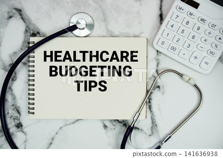 Healthcare Budgeting Tips text written on notepad with stethoscope and calculator on marble background Healthcare Budgeting Tips text written on notepad with stethoscope and calculator on marble background 141636938