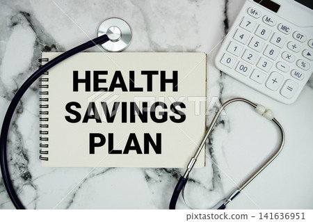 Health Savings Plan text written on notepad with stethoscope and calculator on marble background Health Savings Plan text written on notepad with stethoscope and calculator on marble background 141636951