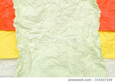 crumpled light green paper on top of layers of orange yellow and white paper crumpled light green paper on top of layers of orange yellow and white paper 141637109