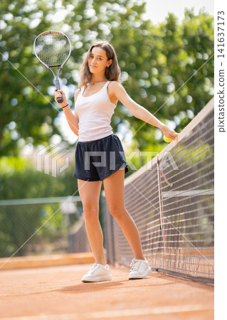 Tennis player stands on court ready for match on sunny day Tennis player stands on court ready for match on sunny day 141637173