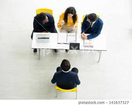 Job interview concept. Diverse hr team doing job interview with a man in business office. Human resources team interviewing a potential job candidate. Hiring, employment, and recruitment concept. Job interview concept. Diverse hr team doing job interview with a man in business office. Human resources team interviewing a potential job candidate. Hiring, employment, and recruitment concept. 141637327