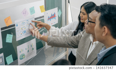 Business team analyzing marketing data and financial charts during corporate strategy meeting, collaborative planning session with analytics dashboard, brainstorming and project development discussion Business team analyzing marketing data and financial charts during corporate strategy meeting, collaborative planning session with analytics dashboard, brainstorming and project development discussion 141637347