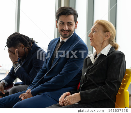 Diverse professionals from different generations and cultural backgrounds waiting together before a business interview in office. Workplace diversity, recruitment, inclusion, teamwork. Recruitment. Diverse professionals from different generations and cultural backgrounds waiting together before a business interview in office. Workplace diversity, recruitment, inclusion, teamwork. Recruitment. 141637358