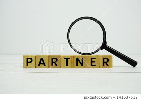 PARTNER alphabet letters with magnifying glass on wooden background PARTNER alphabet letters with magnifying glass on wooden background 141637512
