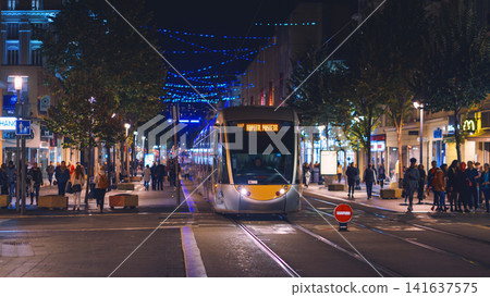 Nice, France - November 2, 2018 - Tram at night on Massena square with pedestrians Nice, France - November 2, 2018 - Tram at night on Massena square with pedestrians 141637575