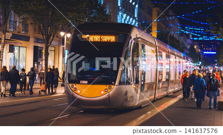 Nice, France - November 2, 2018 - Tram at night on Massena square with pedestrians Nice, France - November 2, 2018 - Tram at night on Massena square with pedestrians 141637576