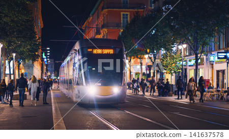Nice, France - November 2, 2018 - Tram at night on Massena square with pedestrians Nice, France - November 2, 2018 - Tram at night on Massena square with pedestrians 141637578