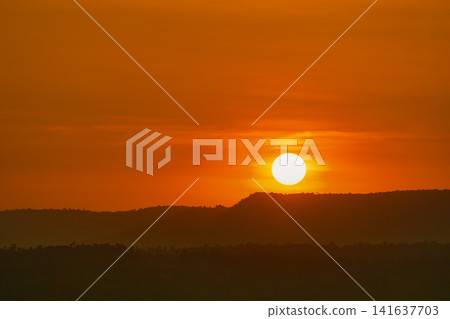 Golden sunrise over layered mountain forest landscape with glowing orange sky. Peaceful natural scenery. Travel, nature, wellness and outdoor adventure concepts. Tranquil nature. travel destination. Golden sunrise over layered mountain forest landscape with glowing orange sky. Peaceful natural scenery. Travel, nature, wellness and outdoor adventure concepts. Tranquil nature. travel destination. 141637703
