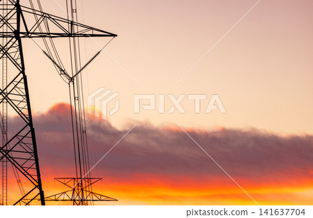 High voltage electricity transmission tower against sunset sky. Power infrastructure, energy distribution, utility network and electrical engineering. Electricity grid, sustainable energy distribution 141637704