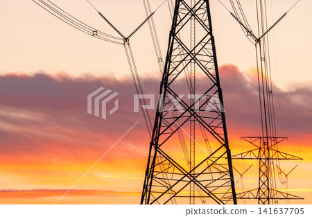 High voltage electricity transmission tower against sunset sky. Power infrastructure, energy distribution, utility network and electrical engineering. Electricity grid, sustainable energy distribution High voltage electricity transmission tower against sunset sky. Power infrastructure, energy distribution, utility network and electrical engineering. Electricity grid, sustainable energy distribution 141637705