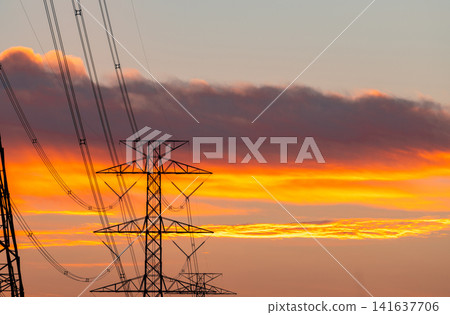 High voltage electricity transmission tower against sunset sky. Power infrastructure, energy distribution, utility network and electrical engineering. Electricity grid, sustainable energy distribution 141637706