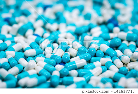 Close up background of blue and white pharmaceutical capsules. Modern medicine, healthcare, pharmacy, prescription drugs, biotechnology and pharmaceutical industry. Modern pharmaceutical research. Close up background of blue and white pharmaceutical capsules. Modern medicine, healthcare, pharmacy, prescription drugs, biotechnology and pharmaceutical industry. Modern pharmaceutical research. 141637713