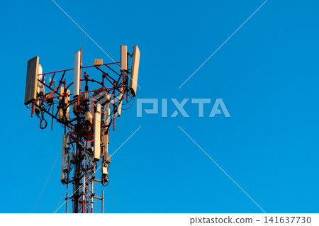 Telecommunication tower with multiple cellular antennas against blue sky, modern wireless network infrastructure supporting 4G, 5G, broadband internet, mobile communication and digital connectivity. Telecommunication tower with multiple cellular antennas against blue sky, modern wireless network infrastructure supporting 4G, 5G, broadband internet, mobile communication and digital connectivity. 141637730