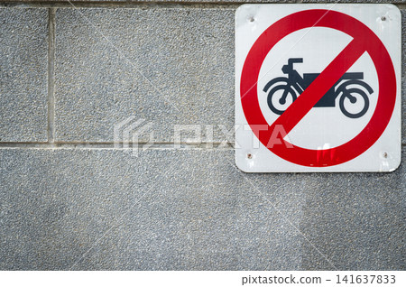 Motorcycle prohibited traffic sign mounted on concrete wall. Road safety regulations, restricted access, urban transportation control and public safety. Traffic restriction, transportation policy. Motorcycle prohibited traffic sign mounted on concrete wall. Road safety regulations, restricted access, urban transportation control and public safety. Traffic restriction, transportation policy. 141637833