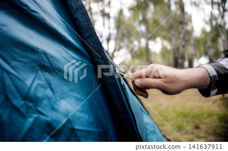 Man Setting Up Tent During Outdoor Camping Trip 141637911