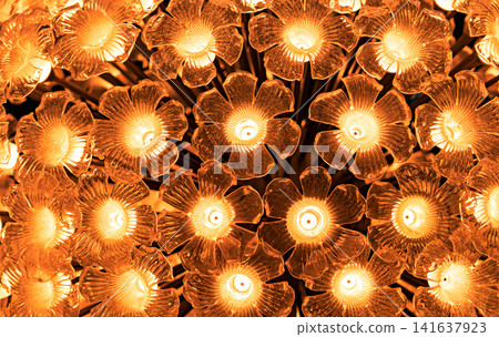 Luxury floral glass chandelier with glowing warm light, elegant flower shaped lighting fixture creating decorative abstract pattern for modern hotel, restaurant, home interior and architectural design Luxury floral glass chandelier with glowing warm light, elegant flower shaped lighting fixture creating decorative abstract pattern for modern hotel, restaurant, home interior and architectural design 141637923