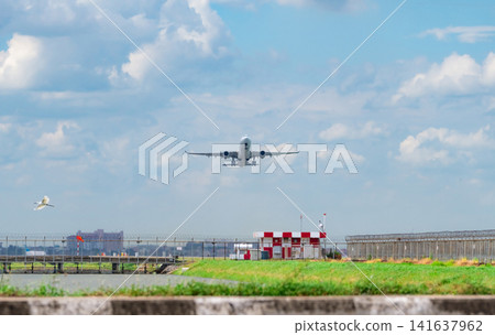 Commercial passenger airplane on final approach with landing gear deployed above airport perimeter. Aviation, airline transportation, runway operations, flight safety and modern air travel. Commercial passenger airplane on final approach with landing gear deployed above airport perimeter. Aviation, airline transportation, runway operations, flight safety and modern air travel. 141637962