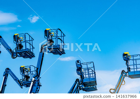 Articulated boom lift fleet with telescopic aerial work platforms against sky. Construction equipment rental, industrial maintenance, hydraulic access systems, engineering services and elevated work. Articulated boom lift fleet with telescopic aerial work platforms against sky. Construction equipment rental, industrial maintenance, hydraulic access systems, engineering services and elevated work. 141637966