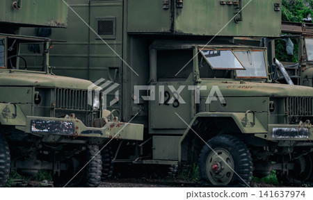 Abandoned rusty military trucks parked in storage yard with visible corrosion and aging equipment. Fleet depreciation, industrial maintenance, transportation logistics, recycling and economic decline. Abandoned rusty military trucks parked in storage yard with visible corrosion and aging equipment. Fleet depreciation, industrial maintenance, transportation logistics, recycling and economic decline. 141637974