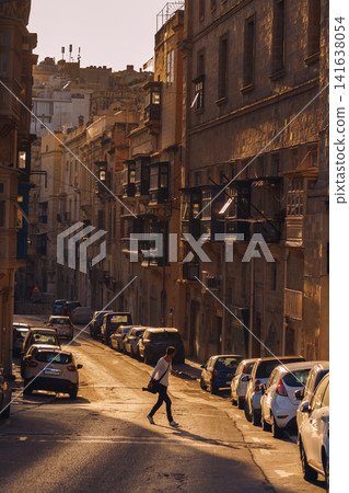 VALLETTA, MALTA - NOVEMBER 12, 2018 - Hilly ancient streets view with colourful balconies, people and cars in the medieval city VALLETTA, MALTA - NOVEMBER 12, 2018 - Hilly ancient streets view with colourful balconies, people and cars in the medieval city 141638054