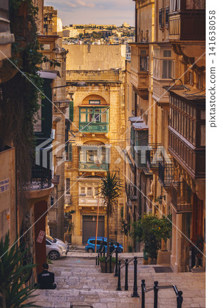 VALLETTA, MALTA - NOVEMBER 12, 2018 - Hilly ancient streets view with colourful balconies, people and cars in the medieval city VALLETTA, MALTA - NOVEMBER 12, 2018 - Hilly ancient streets view with colourful balconies, people and cars in the medieval city 141638058