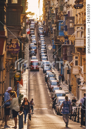 VALLETTA, MALTA - NOVEMBER 12, 2018 - Hilly ancient streets view with colourful balconies, people and cars in the medieval city VALLETTA, MALTA - NOVEMBER 12, 2018 - Hilly ancient streets view with colourful balconies, people and cars in the medieval city 141638059