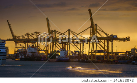 BARCELONA, SPAIN - NOVEMBER 09, 2018 - Container cargo ships and docks with cranes loading and unloading goods and the pilot boat in the sea BARCELONA, SPAIN - NOVEMBER 09, 2018 - Container cargo ships and docks with cranes loading and unloading goods and the pilot boat in the sea 141638078