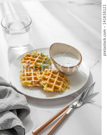 Vegetarian potato waffles with natural yogurt and dill on a plate on a marble background Vegetarian potato waffles with natural yogurt and dill on a plate on a marble background 141638121