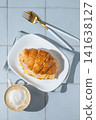 A golden croissant sandwich with ham and cheese on a white plate on a tile background 141638127