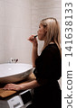 Morning routine: A beautiful blonde brushing her teeth in the bathroom. Side view. 141638133