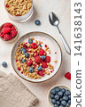 Natural greek yogurt with granola, blueberry and raspberry in a bowl on a light textured background 141638143