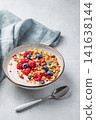 Natural greek yogurt with granola, blueberry and raspberry in a bowl on a light concrete background 141638144
