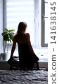 A sexy beautiful woman in a black erotic negligee stands near the window in the bedroom. 141638145