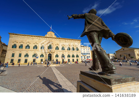VALLETTA, MALTA - NOVEMBER 12, 2018 - Statue of Manuel Dimech and exterior view of the Auberge de Castille in Castille Square VALLETTA, MALTA - NOVEMBER 12, 2018 - Statue of Manuel Dimech and exterior view of the Auberge de Castille in Castille Square 141638189