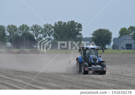 Blue Tractor Cultivating Dry Dusty Field Blue Tractor Cultivating Dry Dusty Field 141638276