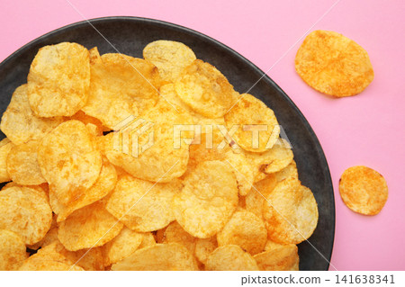 Potato chips on plate on pink background Potato chips on plate on pink background 141638341