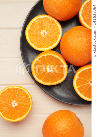 Fresh orange fruit on dark plate on light wooden background. Vertical photo Fresh orange fruit on dark plate on light wooden background. Vertical photo 141638364