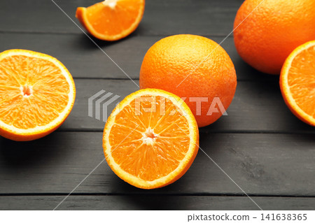 Whole and half of orange fruit on black wooden background. Whole and half of orange fruit on black wooden background. 141638365
