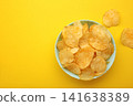 Delicious potato chips in bowl on yellow background. 141638389
