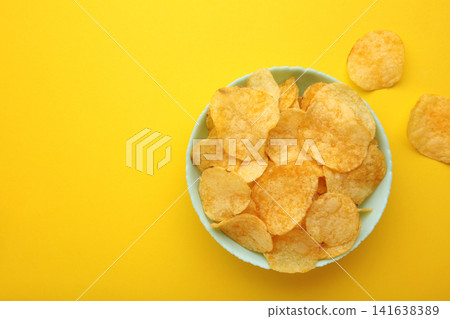 Delicious potato chips in bowl on yellow background. Delicious potato chips in bowl on yellow background. 141638389