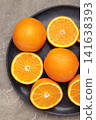 Fresh orange fruit on dark plate on grey concrete background. Vertical photo 141638393