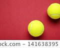 Two yellow tennis balls on red background 141638395