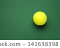 Bright yellow tennis ball on green background. Space for text 141638398