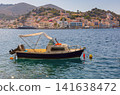 Small Motor Boat Anchored off Symi Harbor with Waterfront Town in Greece 141638472