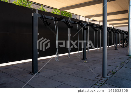 Modern covered bike parking racks in Fuerstenfeldbruck, Bavaria, Germany, empty bicycle parking area in urban street on sunny day Modern covered bike parking racks in Fuerstenfeldbruck, Bavaria, Germany, empty bicycle parking area in urban street on sunny day 141638506