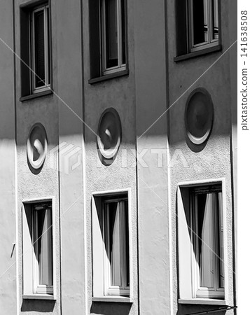 Black and white Munich building facade with strong vertical architectural elements and sharp sunlight shadows, modern urban geometry and minimalist city architecture detail in Germany Black and white Munich building facade with strong vertical architectural elements and sharp sunlight shadows, modern urban geometry and minimalist city architecture detail in Germany 141638508