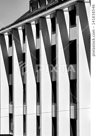 Black and white Munich building facade with strong vertical architectural elements and sharp sunlight shadows, modern urban geometry and minimalist city architecture detail in Germany Black and white Munich building facade with strong vertical architectural elements and sharp sunlight shadows, modern urban geometry and minimalist city architecture detail in Germany 141638546