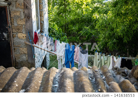 Colorful laundry drying on clothesline outside old village house - traditional rural life Romania Colorful laundry drying on clothesline outside old village house - traditional rural life Romania 141638553