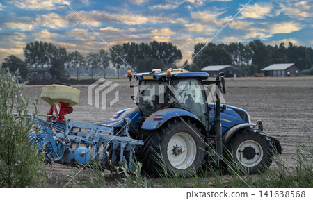 Side view of a blue tractor working in a dry, dusty field Side view of a blue tractor working in a dry, dusty field 141638568